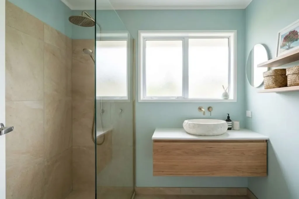 Custom Small Bathroom Renovations by Bathroom Renovations Tauranga featuring a compact walk-in shower, floating timber vanity, and soft natural light.